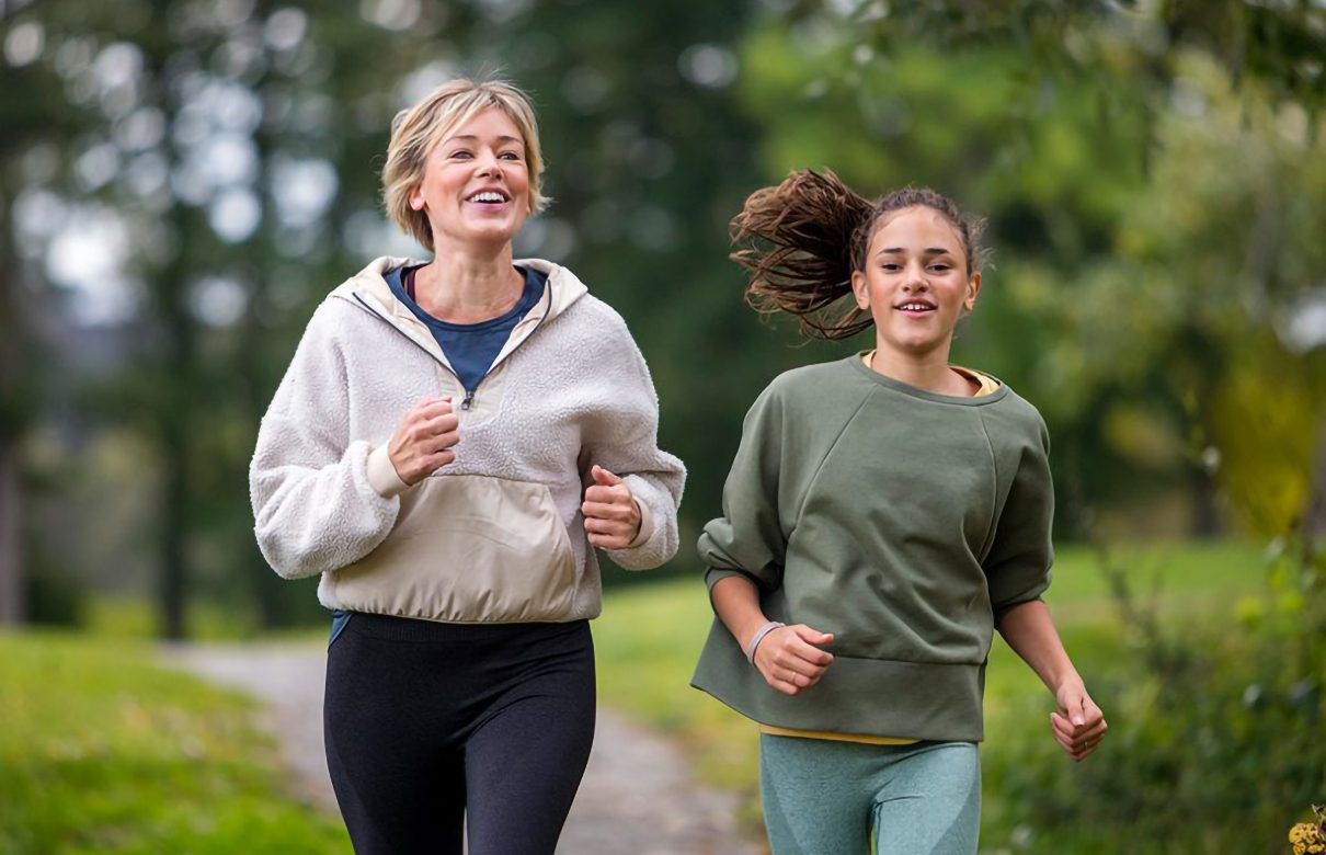 Woman and girl running in a park setting.